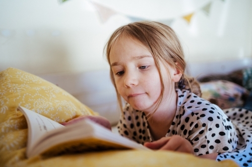 Young girl reading a book at home