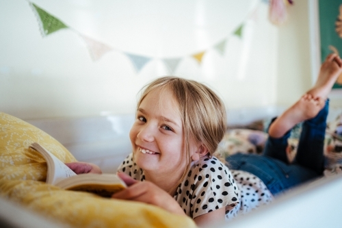 Young girl reading a book at home - Australian Stock Image