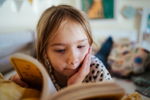 Young girl reading a book at home - Australian Stock Image