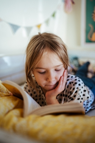 Young girl reading a book at home - Australian Stock Image