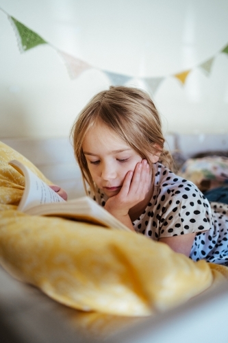 Young girl reading a book at home - Australian Stock Image