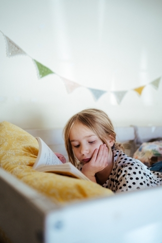 Young girl reading a book at home - Australian Stock Image