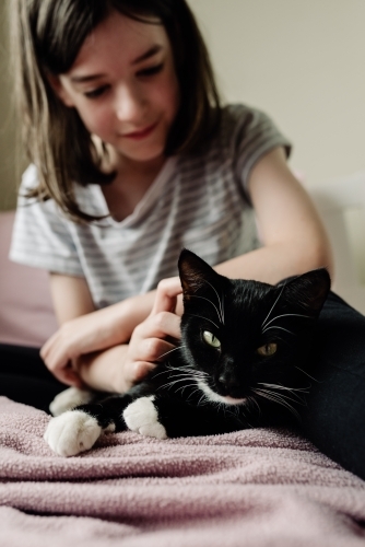 Young girl relaxing with her cat on her bed.