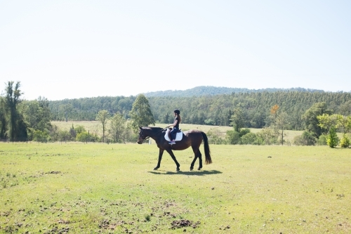 Young girl riding a horse in a paddock - Australian Stock Image