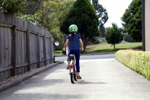 Young girl riding bike from behind - Australian Stock Image