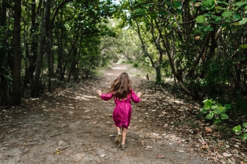 Young girl running through along a bush path