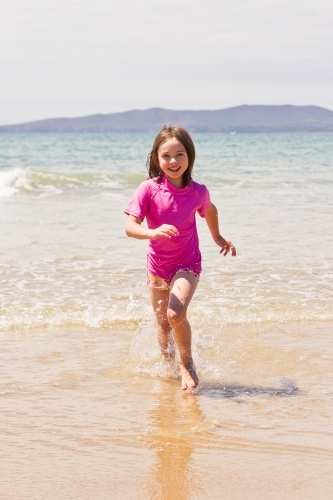 Young girl running through waves - Australian Stock Image