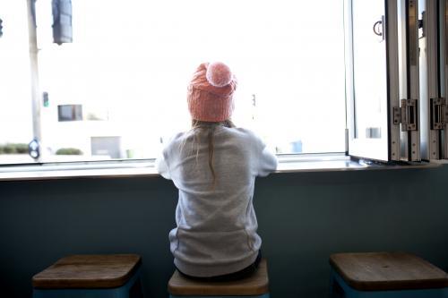 Young girl sitting in a cafe window looking out - Australian Stock Image