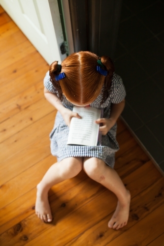 Young girl sitting on the floor reading a book