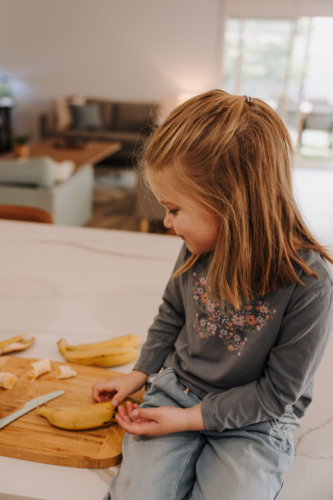Young girl sitting on the kitchen countertop. - Australian Stock Image