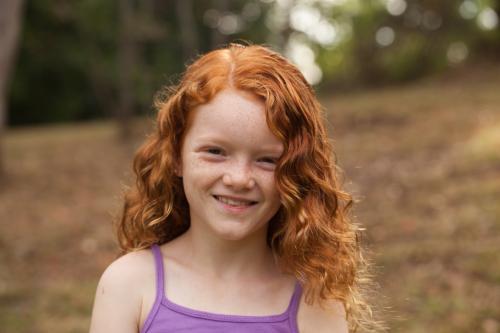 Young girl smiling in an open field - Australian Stock Image