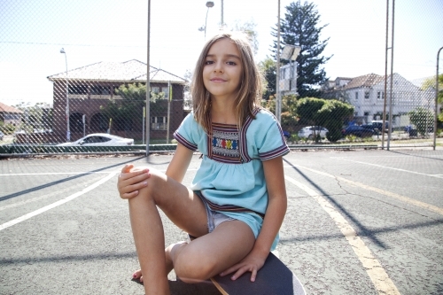 Young girl smiling sitting on skateboard
