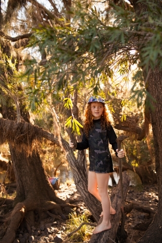 Young girl standing among trees in afternoon light - Australian Stock Image