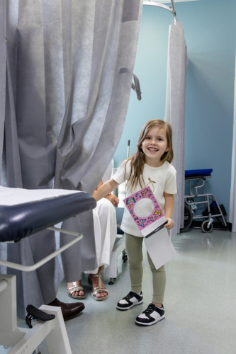 Young girl standing behind curtains holding a notebook - Australian Stock Image
