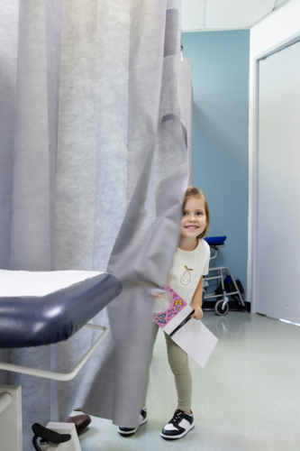 Young girl standing behind curtains holding a notebook - Australian Stock Image