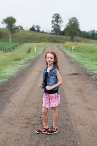 Young girl standing on a dirt track