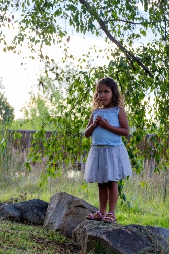 Young girl standing on a rock looking worried - Australian Stock Image