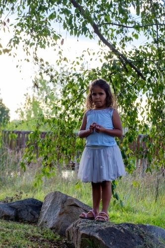Young girl standing on a rock near wooden bridge - Australian Stock Image