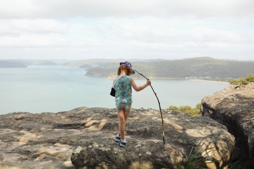 Young girl standing on a rock overlooking water - Australian Stock Image