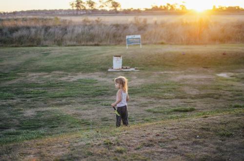 Young girl standing on rural golf course at sunset