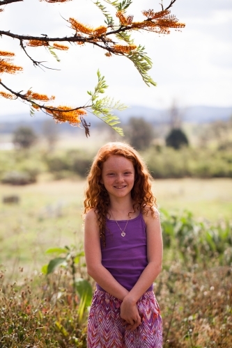 Young girl standing under a Silky Oak tree - Australian Stock Image