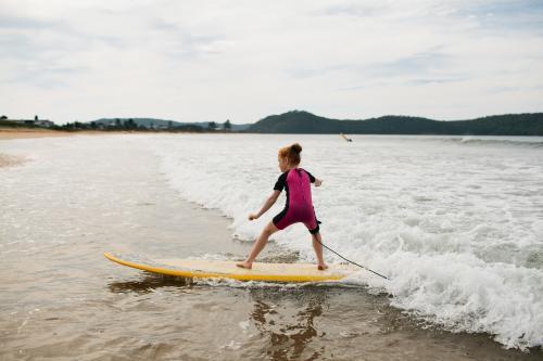 Young girl surfing at the beach - Australian Stock Image