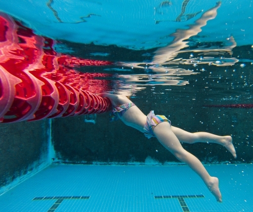 Young girl swimming underwater at a pool - Australian Stock Image