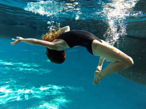 Young girl swimming underwater at a pool - Australian Stock Image
