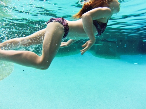Young girl swimming underwater at a pool - Australian Stock Image