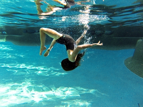 Young girl swimming underwater at a pool - Australian Stock Image