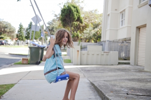 Young girl swinging on a tree swing - Australian Stock Image
