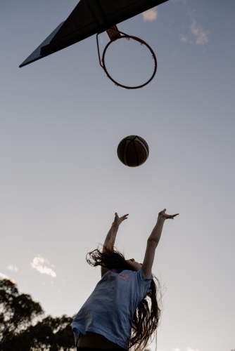 Young girl throwing a basketball into a basketball ring / hoop