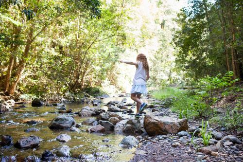 Young girl, walking across rocks at a creek - Australian Stock Image