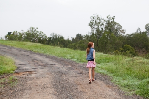 Young girl walking along a dirt road - Australian Stock Image