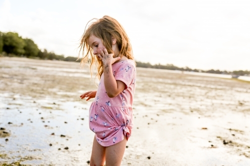 Young girl wandering along and exploring the edge of the ocean - Australian Stock Image