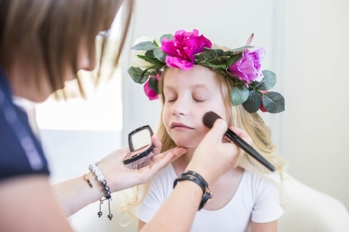 Young girl wearing flower crown getting makeup done - Australian Stock Image