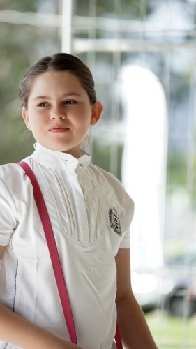 Young girl wearing high-collared shirt with pink strap on shoulder - Australian Stock Image
