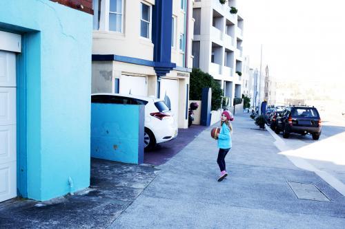 Young girl with basketball running down a blue street