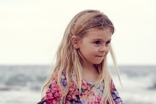 Young girl with blonde hair on beach looking away - Australian Stock Image