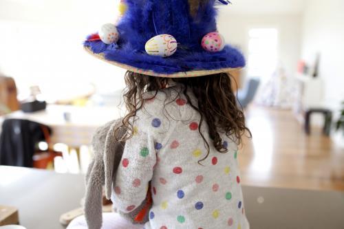 Young girl with handmade easter hat from behind
