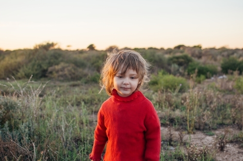 Young girl with messy hair standing in bushland