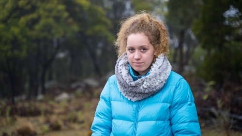 Young girl with red hair and blue jacket outdoors - Australian Stock Image