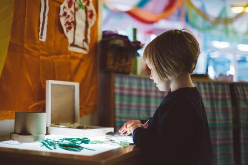 Young girl with short hair at kindergarten doing craft - Australian Stock Image