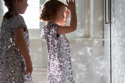 Young girls wearing sparkly dresses playing with the reflected light