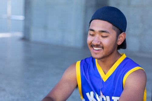 young guy sitting with baseball cap on backwards - Australian Stock Image