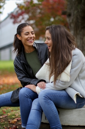 Young happy female couple sitting in the park