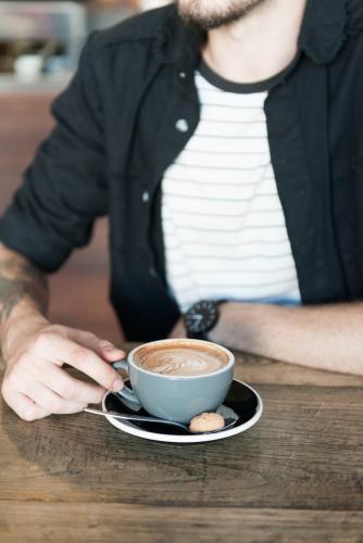Young hipster man drinking coffee in a modern cafe - Australian Stock Image