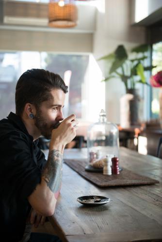 Young hipster man drinking coffee in a modern cafe