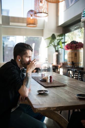 Young hipster man drinking coffee in a modern cafe - Australian Stock Image