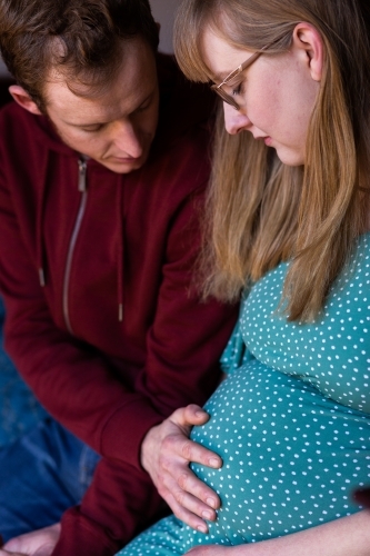 Young husband touching wife's pregnant belly - lifestyle maternity - Australian Stock Image